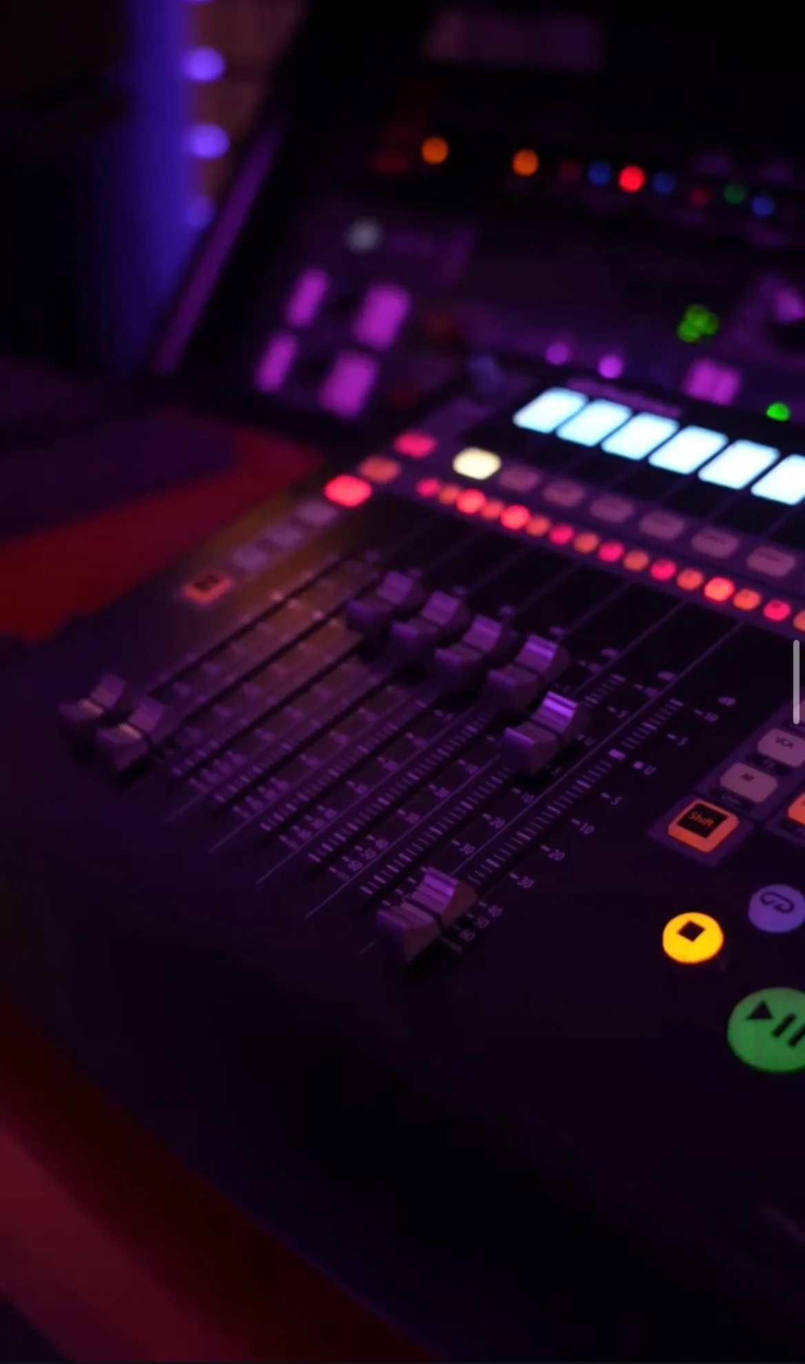 Gros plan sur la console de mixage du Purple Studio, faders et contrôleurs éclairés
